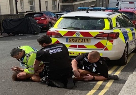 Man shouts 'I can't breathe' as he's pinned down by three police officers
