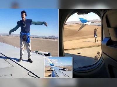A man climbing upon the wing of an Alaska Airlines plane set to depart from McCarran International Airport